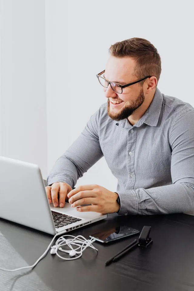 Male blogger happily working on his laptop